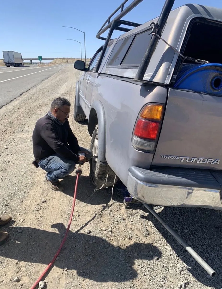 Roadside tire change on a pickup truck beside the highway